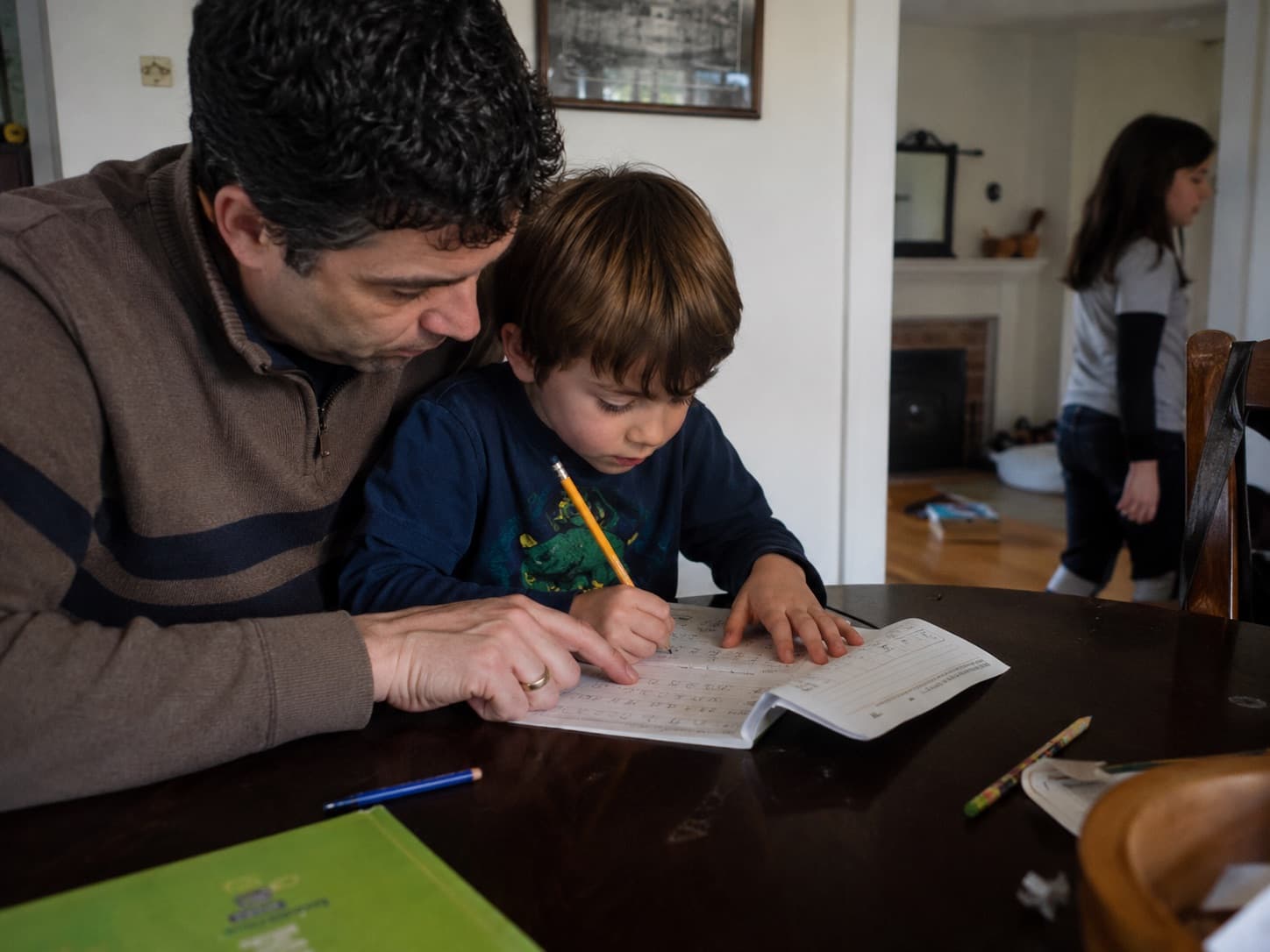 A dad helping his son with homework at the table